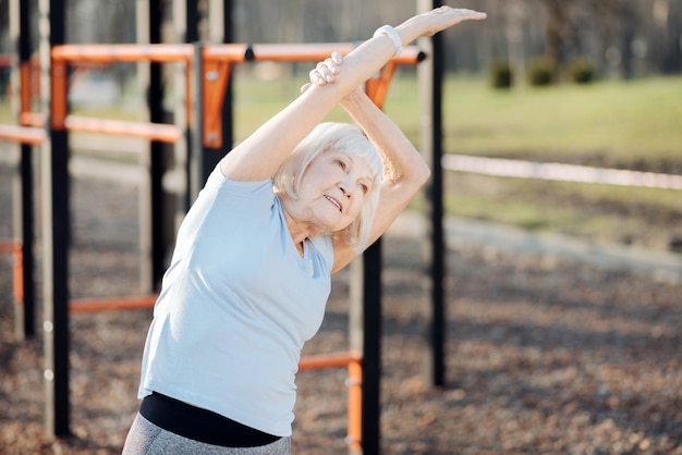 Delighted slim woman smiling and exercising in the open air