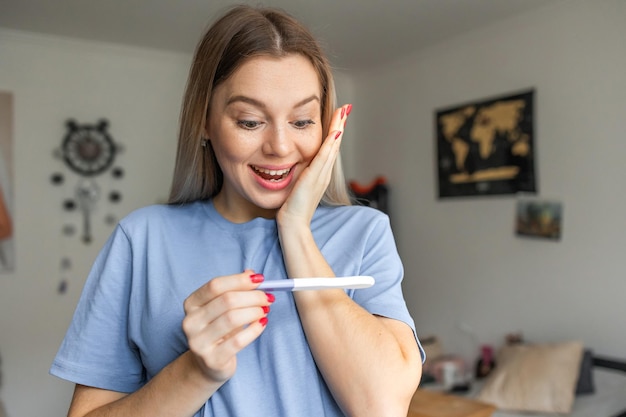Photo delighted and surprised woman holding pregnancy test