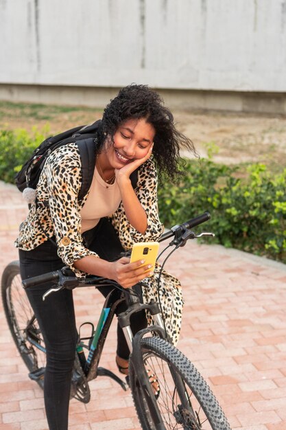 Foto donna deliziata in bicicletta impegnata con lo smartphone