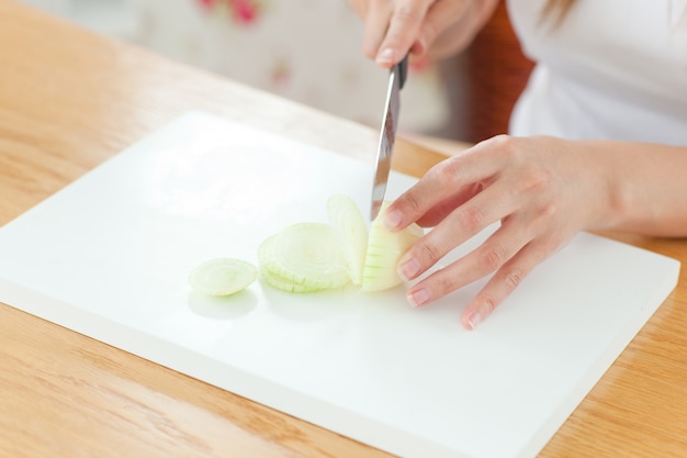 Delighted woman preparing oinion in the kitchen 