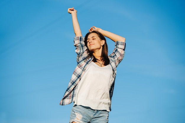 Donna contentissima che si allunga godendosi il sole contro il cielo