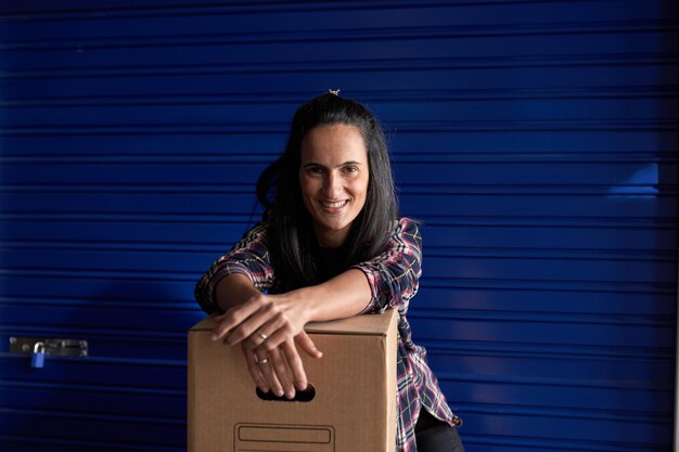 Delighted woman with carton box near storage