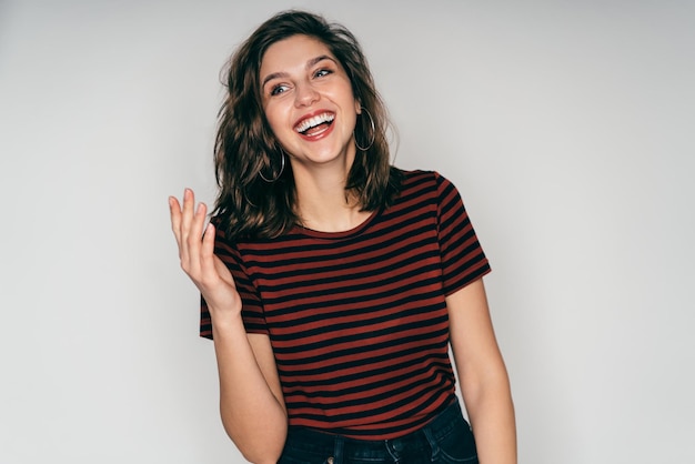 Delighted young beautiful woman in casual outfit posing in studio