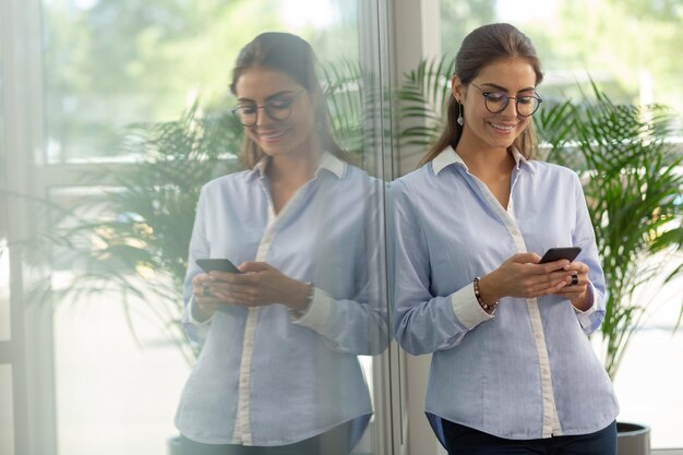 Delighted young office worker looking at her gadget