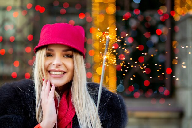 Foto deliziosa ragazza bionda che si diverte con le stelle filanti sullo sfondo del bokeh