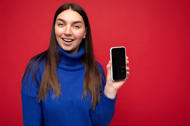 Delightful smiling beautiful happy young brunette woman wearing casual blue sweater isolated