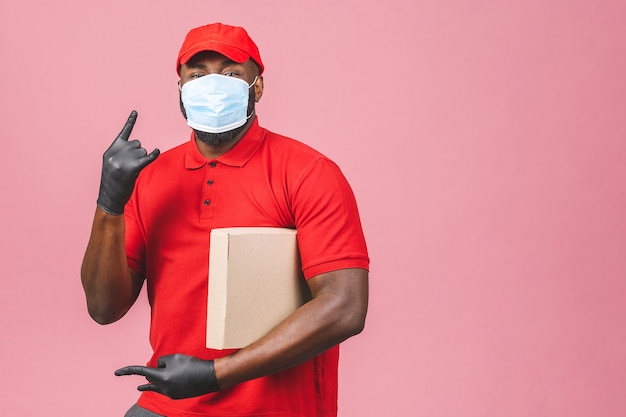 Delivery african american man employee in red cap blank t-shirt uniform face mask gloves hold empty cardboard box