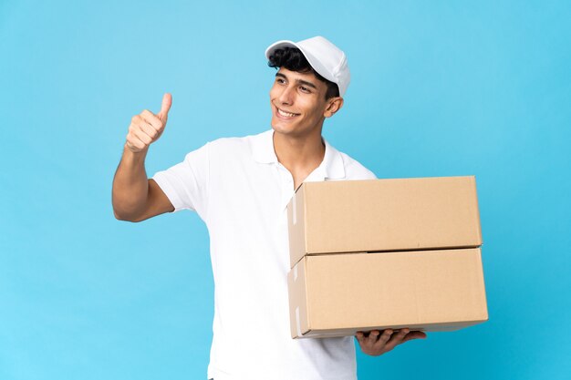 Delivery Argentinian man isolated on blue wall giving a thumbs up gesture