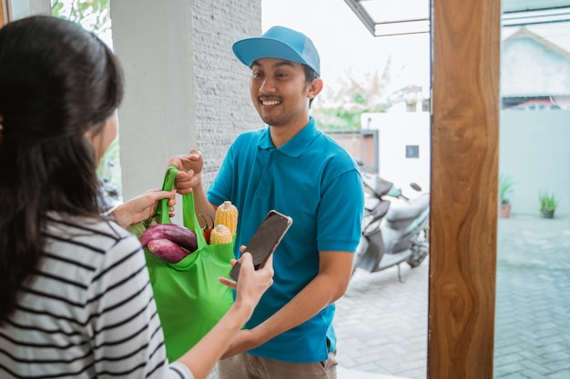 Photo delivery boy is delivering some groceries to woman