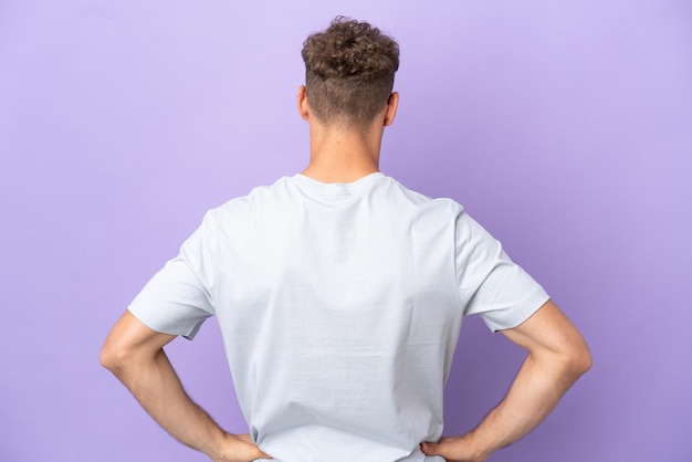 Delivery caucasian man isolated on purple background in back position