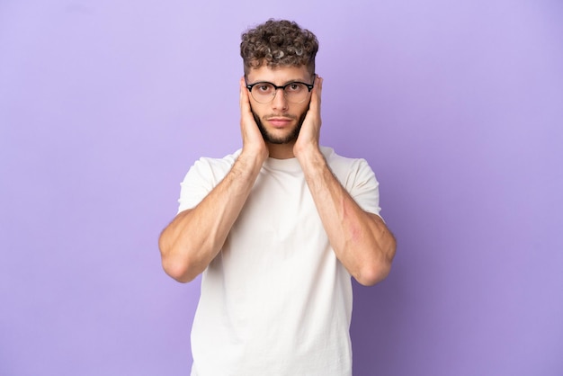 Delivery caucasian man isolated on purple background frustrated and covering ears