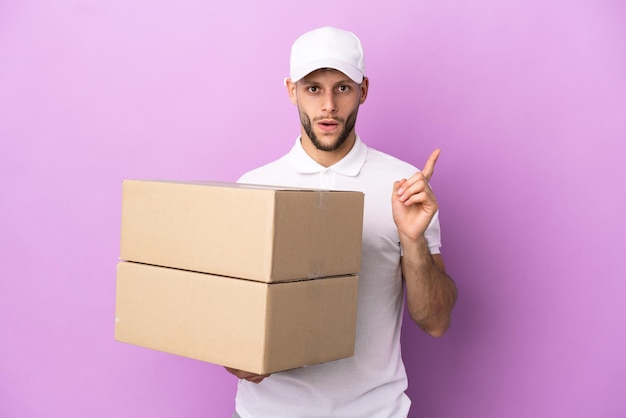 Delivery caucasian man isolated on purple background intending to realizes the solution while lifting a finger up