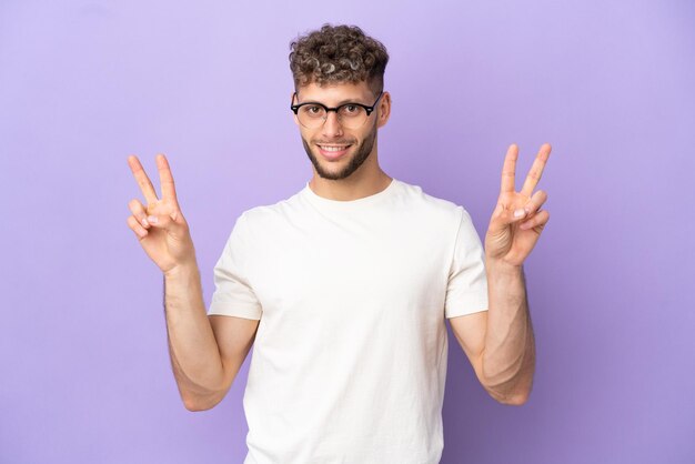 Delivery caucasian man isolated on purple background showing victory sign with both hands