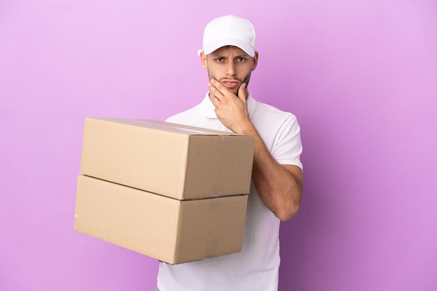 Delivery caucasian man isolated on purple background thinking