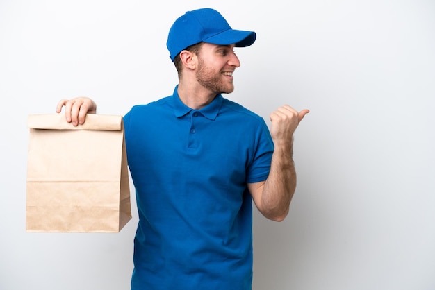 Delivery caucasian man isolated on white background pointing to the side to present a product