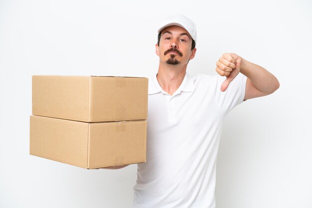 Delivery caucasian man isolated on white background showing thumb down with negative expression