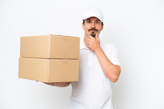 Delivery caucasian man isolated on white background thinking