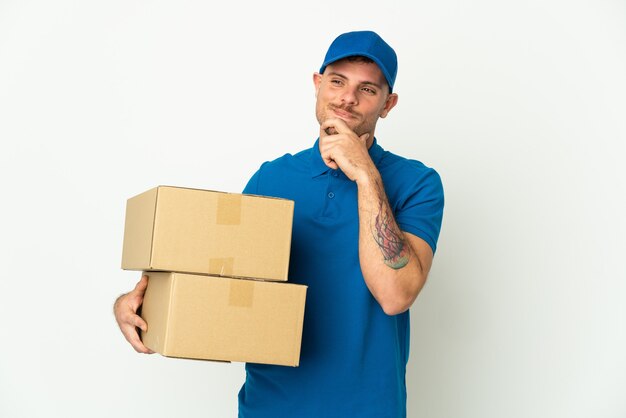 Delivery caucasian man isolated on white wall looking to the side and smiling