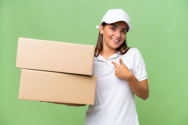 Foto consegna donna caucasica che tiene scatole isolate su sfondo verde croma con espressione facciale a sorpresa