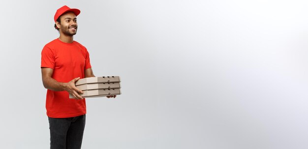 Photo delivery concept portrait of handsome african american pizza delivery man isolated on grey studio background copy space