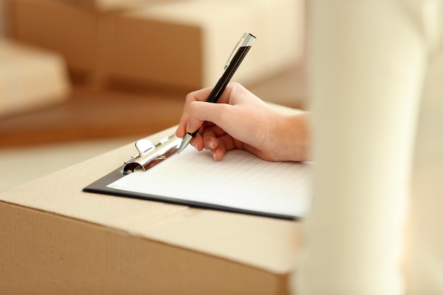 Delivery concept Woman signs papers among parcels close up