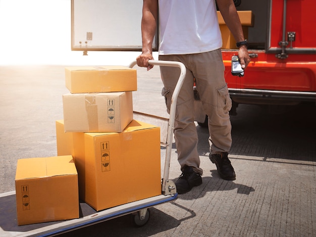 Foto corriere di consegna che guida il carrello con scatole per pacchi per l'invio a una scatola di spedizione per furgone per la consegna del cliente