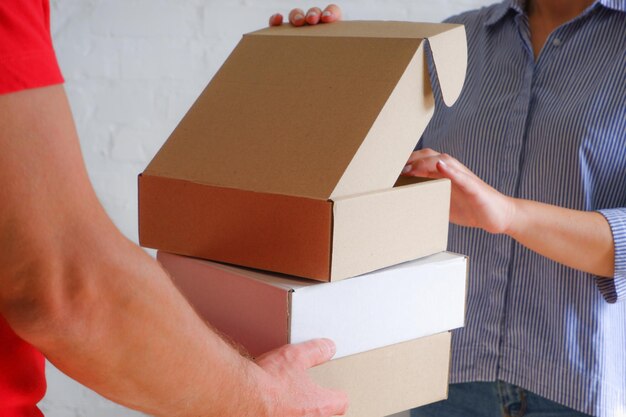 A delivery courier in a red uniform hands over cardboard boxes to a woman Delivery to the office