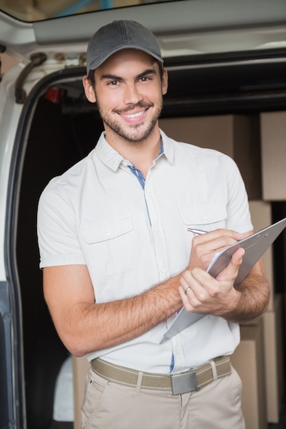 Delivery driver smiling at camera beside his van