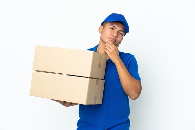 Delivery Ecuadorian man isolated on white wall looking up while smiling