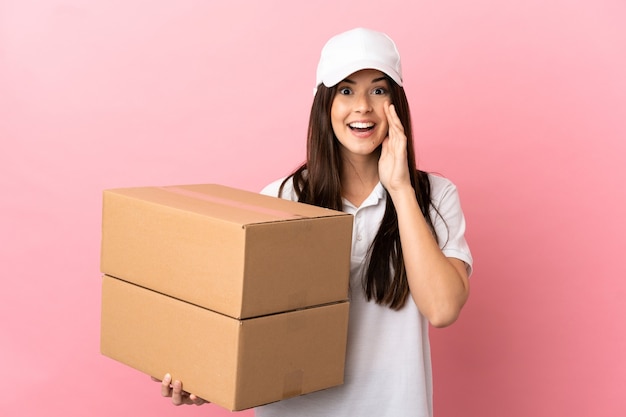 Delivery girl over isolated pink wall shouting with mouth wide open