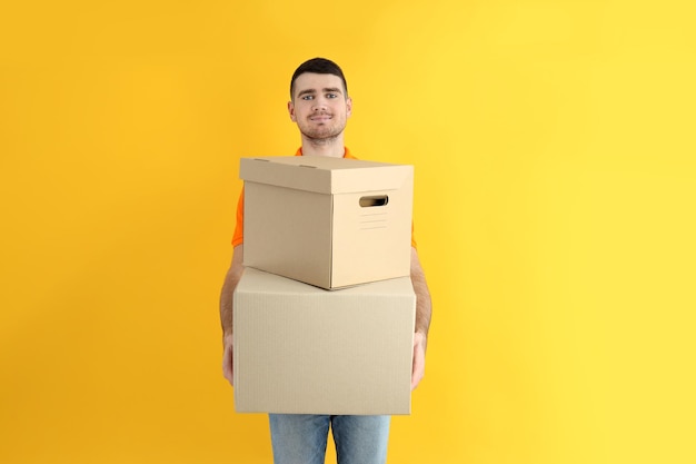 Delivery guy hold boxes on yellow background