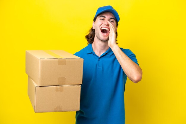 Delivery handsome man isolated on yellow background shouting with mouth wide open