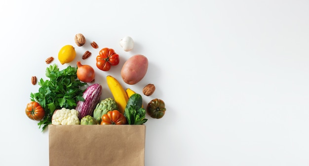 Consegna cibo vegetariano vegano sano in sacchetto di carta frutta e verdura su bianco. shopping supermercato alimentare e concetto di cibo vegano pulito.