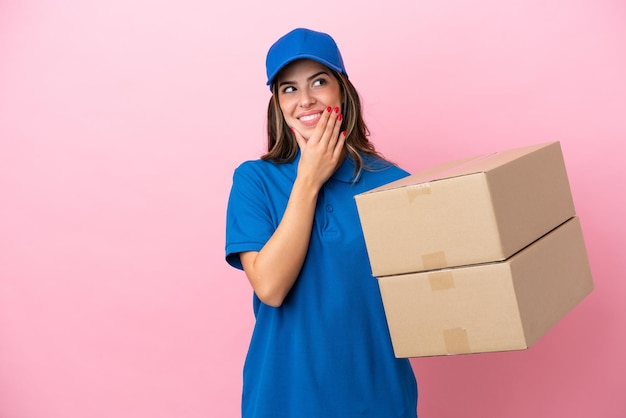 Delivery Italian woman isolated on pink background looking up while smiling