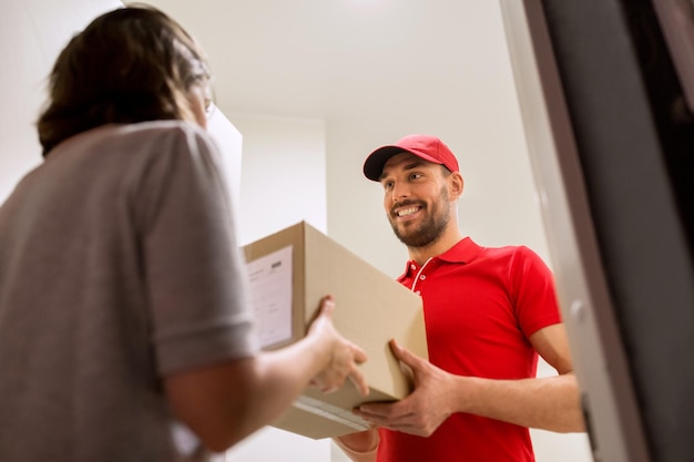 Foto concetto di consegna, posta, persone e spedizione - uomo felice che consegna la cassetta dei pacchi a casa del cliente