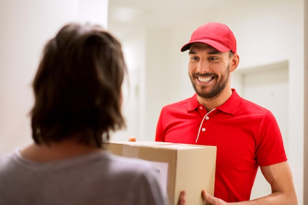 Foto concetto di consegna, posta, persone e spedizione - uomo felice che consegna la cassetta dei pacchi a casa del cliente