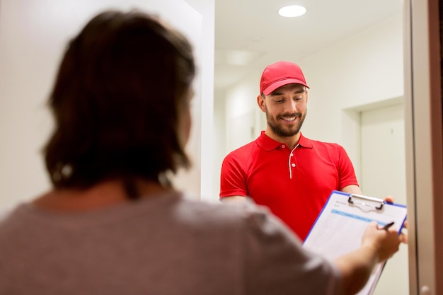 Foto consegna, posta, persone e concetto di spedizione - uomo felice con appunti e modulo di firma del cliente a casa