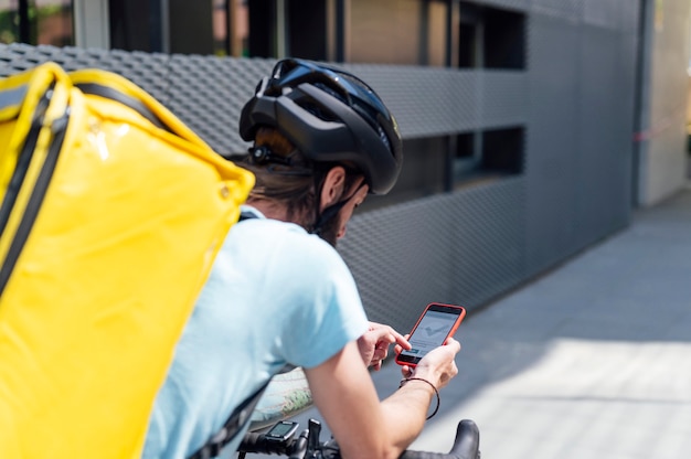 携帯電話で自転車に乗る配達人