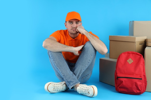 Delivery man on blue background with boxes and backpack