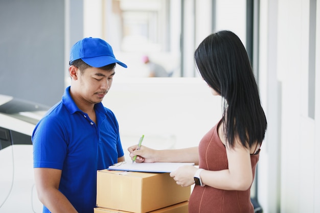 Delivery man in a blue t-shirt holding carton box