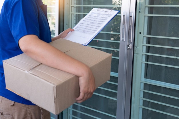 Delivery man in blue uniform handing parcel box for client