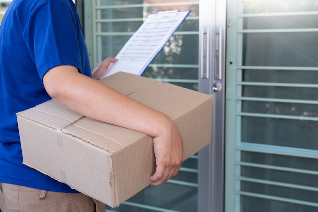 Delivery man in blue uniform handing parcel box for client