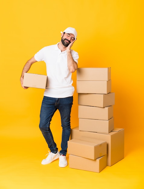 delivery man among boxes making sleep gesture in dorable expression