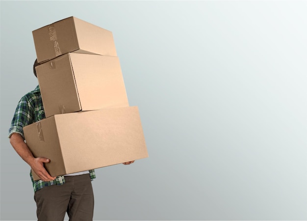 Delivery man carrying stacked boxes in front of face against
background