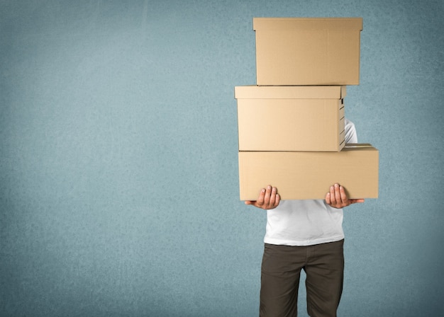 Delivery man carrying stacked boxes in front of face against  background