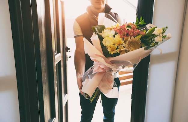 Photo the delivery man delivers a bouquet of beautiful flowers to home