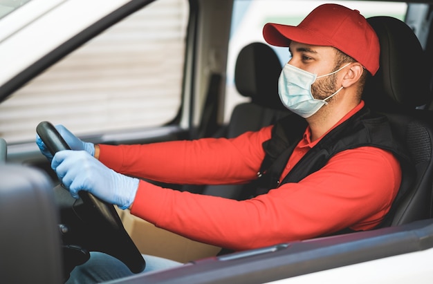 コロナウイルスの発生時にバンを運転する配達員-帽子に焦点を当てる