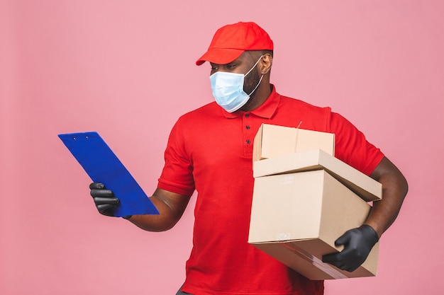 Delivery man employee in red cap blank t-shirt uniform face mask gloves hold empty cardboard box