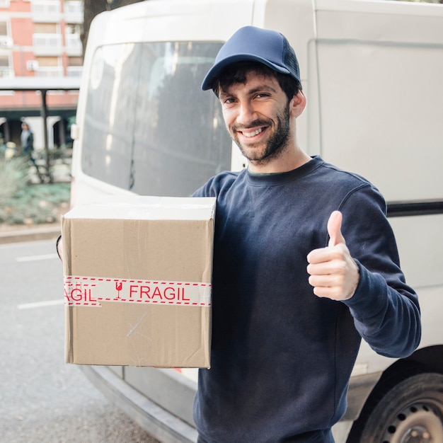 Delivery man gesturing thumbs up while holding parcel