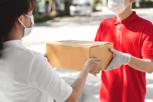 写真 医療用ゴム手袋とマスクの段ボール箱を抱えて配達人